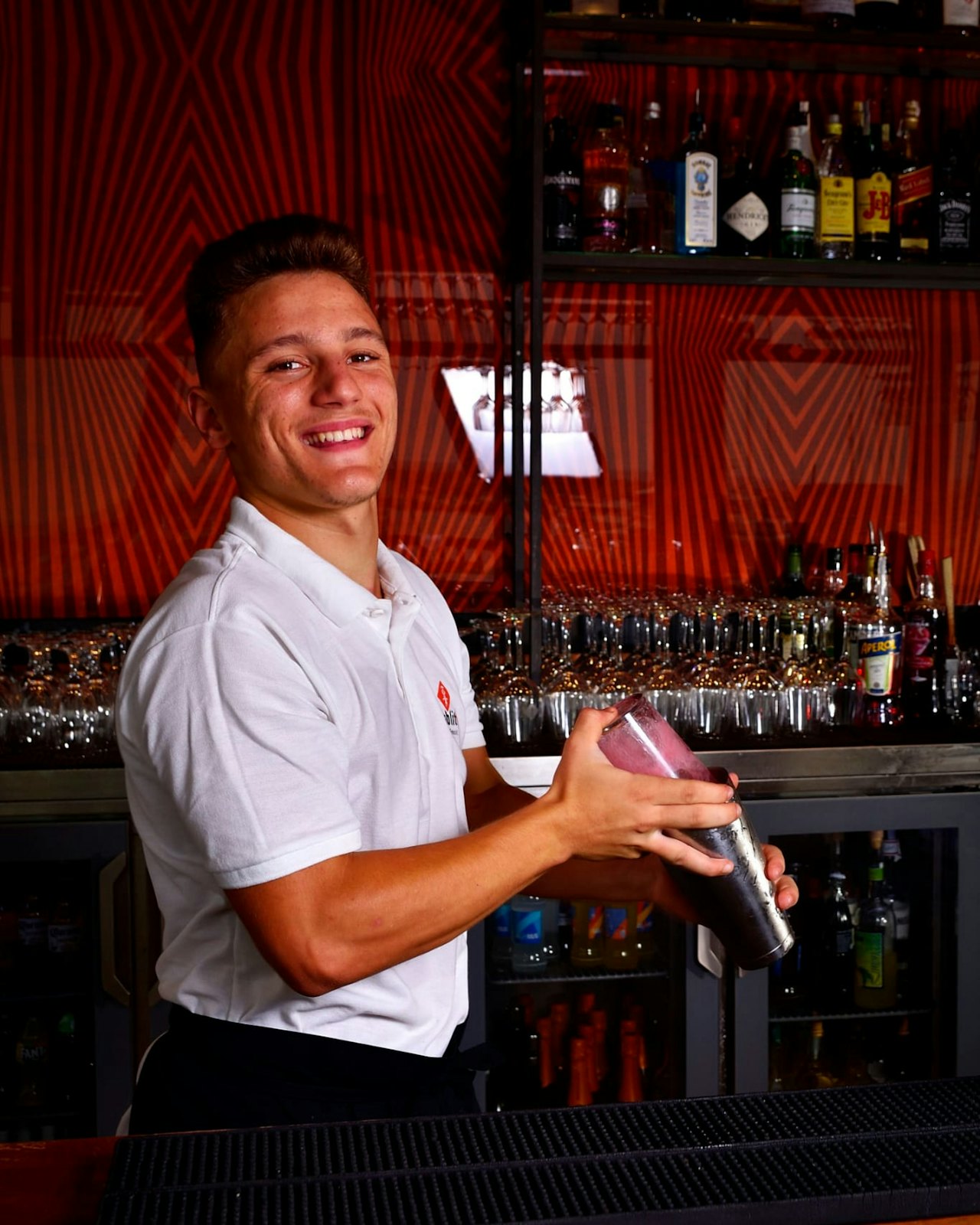 A bartender pouring a cocktail from a shaker