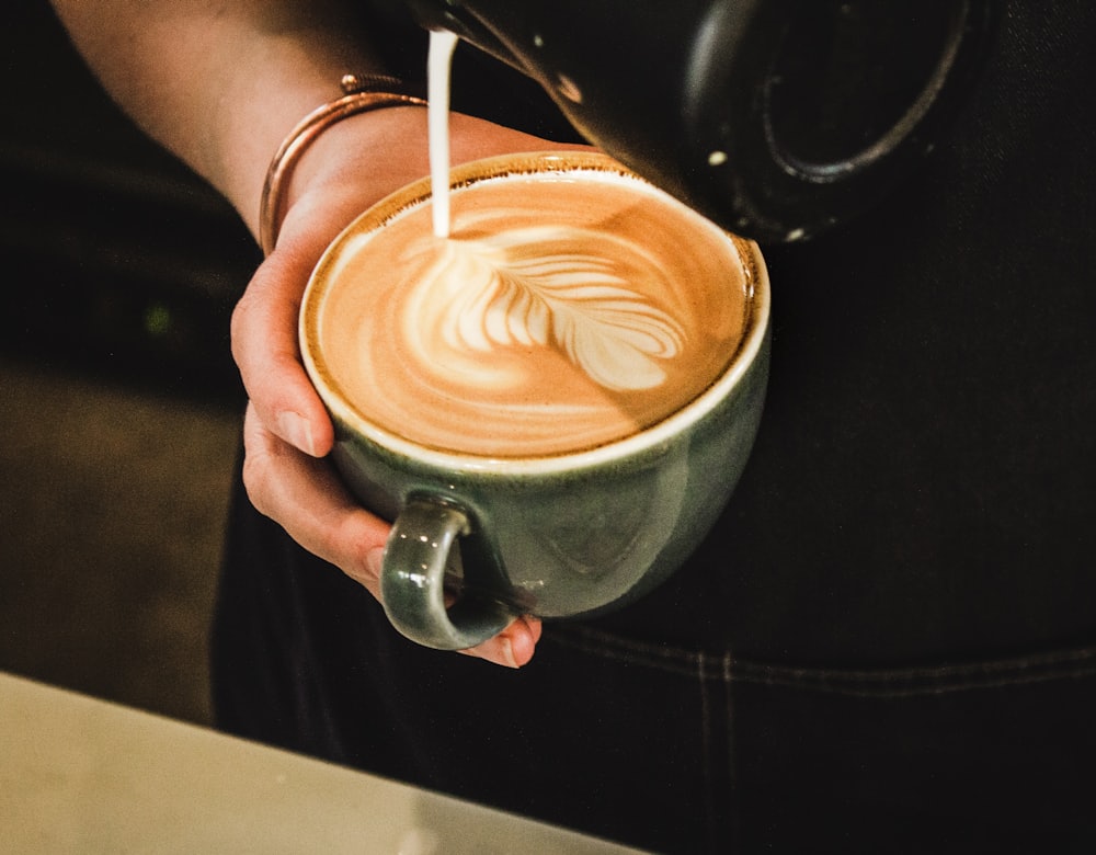 A hand holding a cup of coffee with latte art
