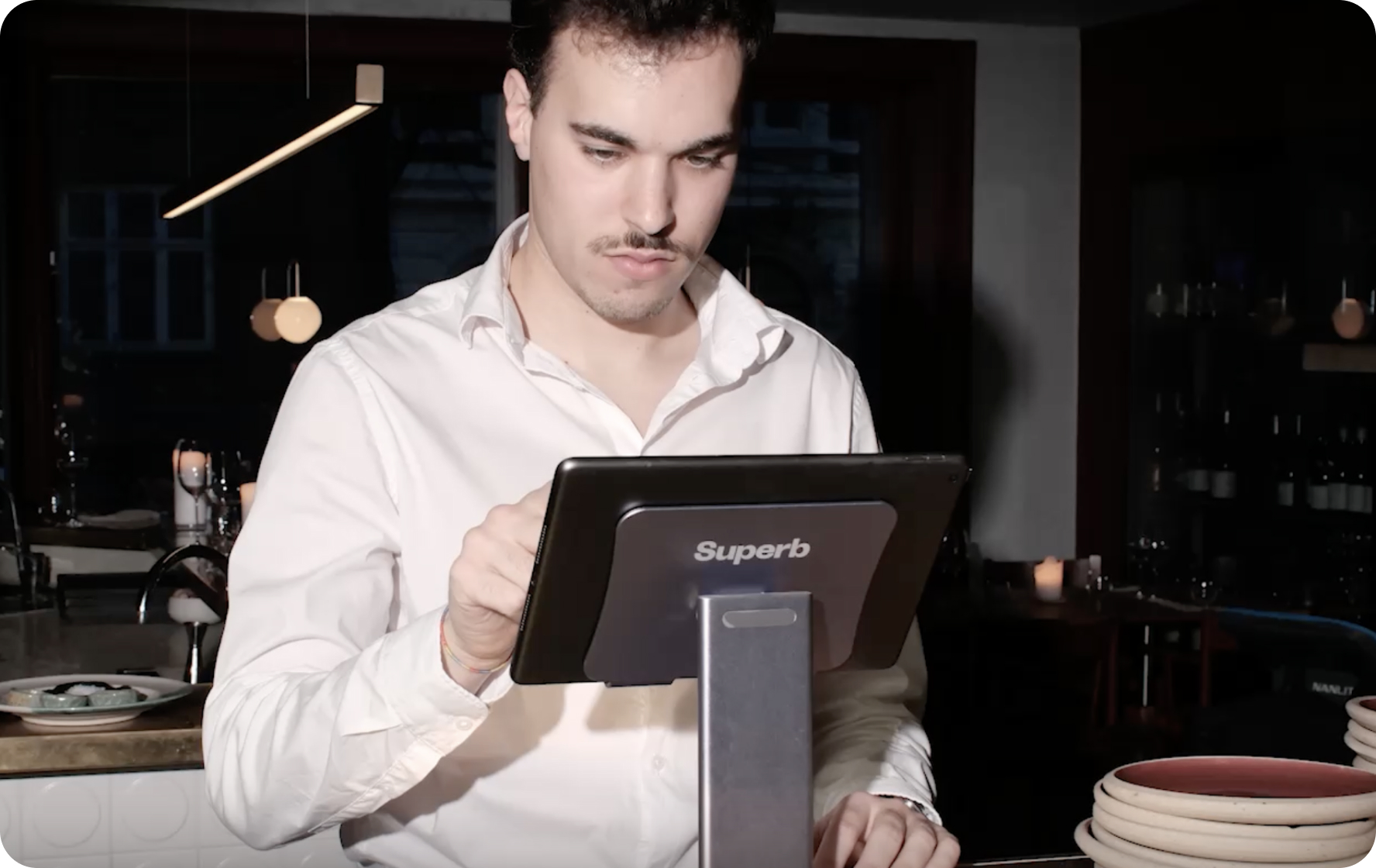 A waiter taking an order on a Superb POS terminal behind the pass