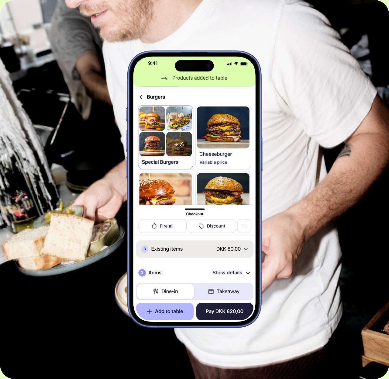 A waiter carrying plates past a phone taking the table's order